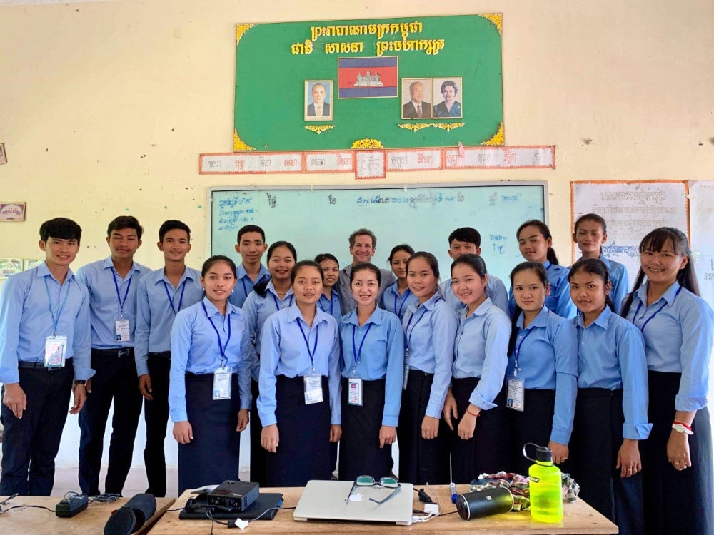 Specialist in Cambodia poses with teacher trainees at end of program
