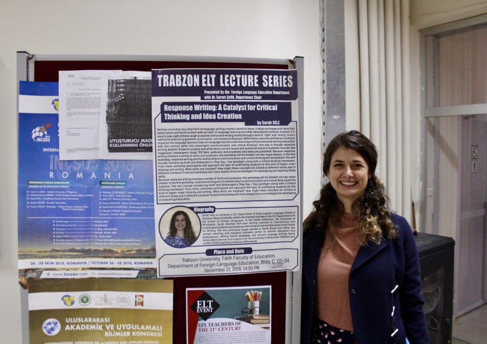 Fellow smiling next to a poster display of her printed article