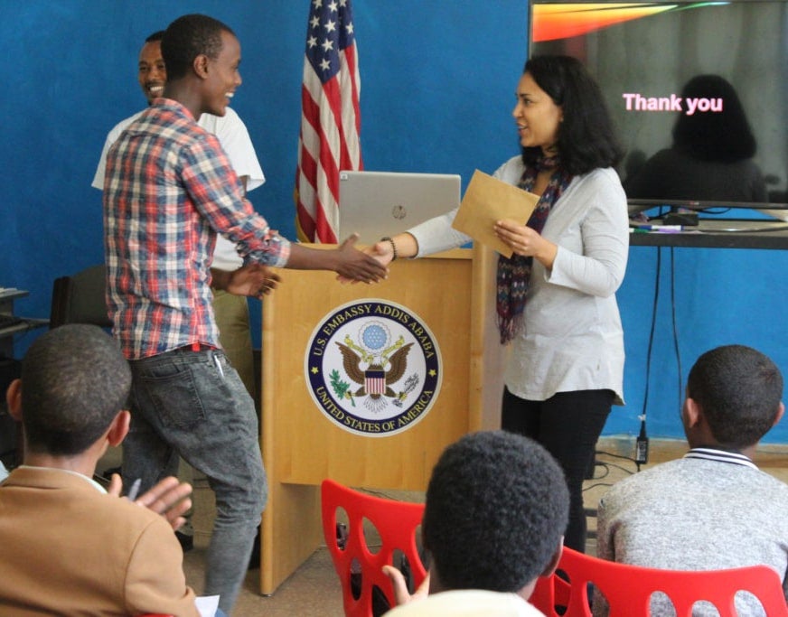 Fellow presents student with participation certificate