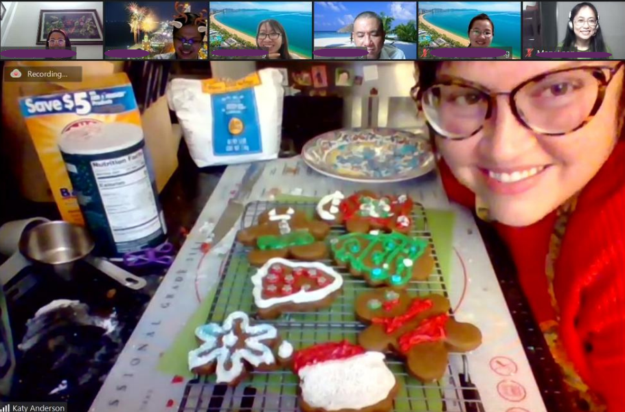 A screenshot of Katherine Anderson teaching an online class - a baking demonstration of gingerbread cookies with ingredients set on the table and colorful icing on the cookies. A row of students in video boxes is visible on the top of the screenshot.