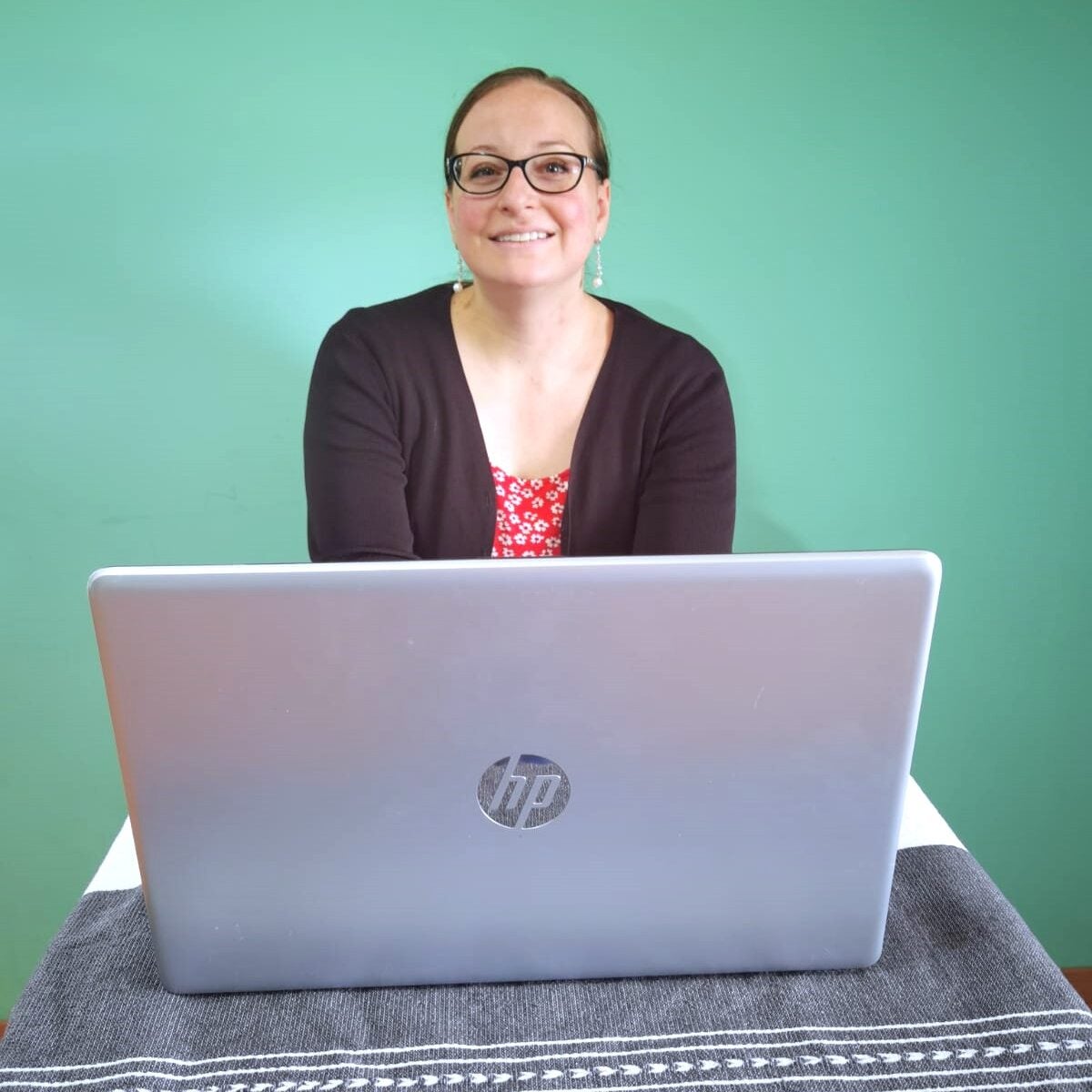 A medium shot of Virtual Educator Ashley Stamper sitting behind a laptop computer and smiling