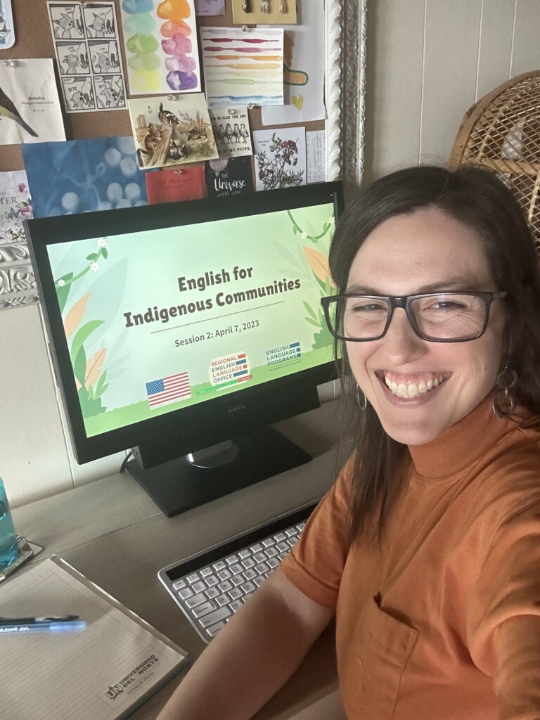 A selfie shot of Virtual Educator Paige Poole sitting behind a laptop computer and smiling
