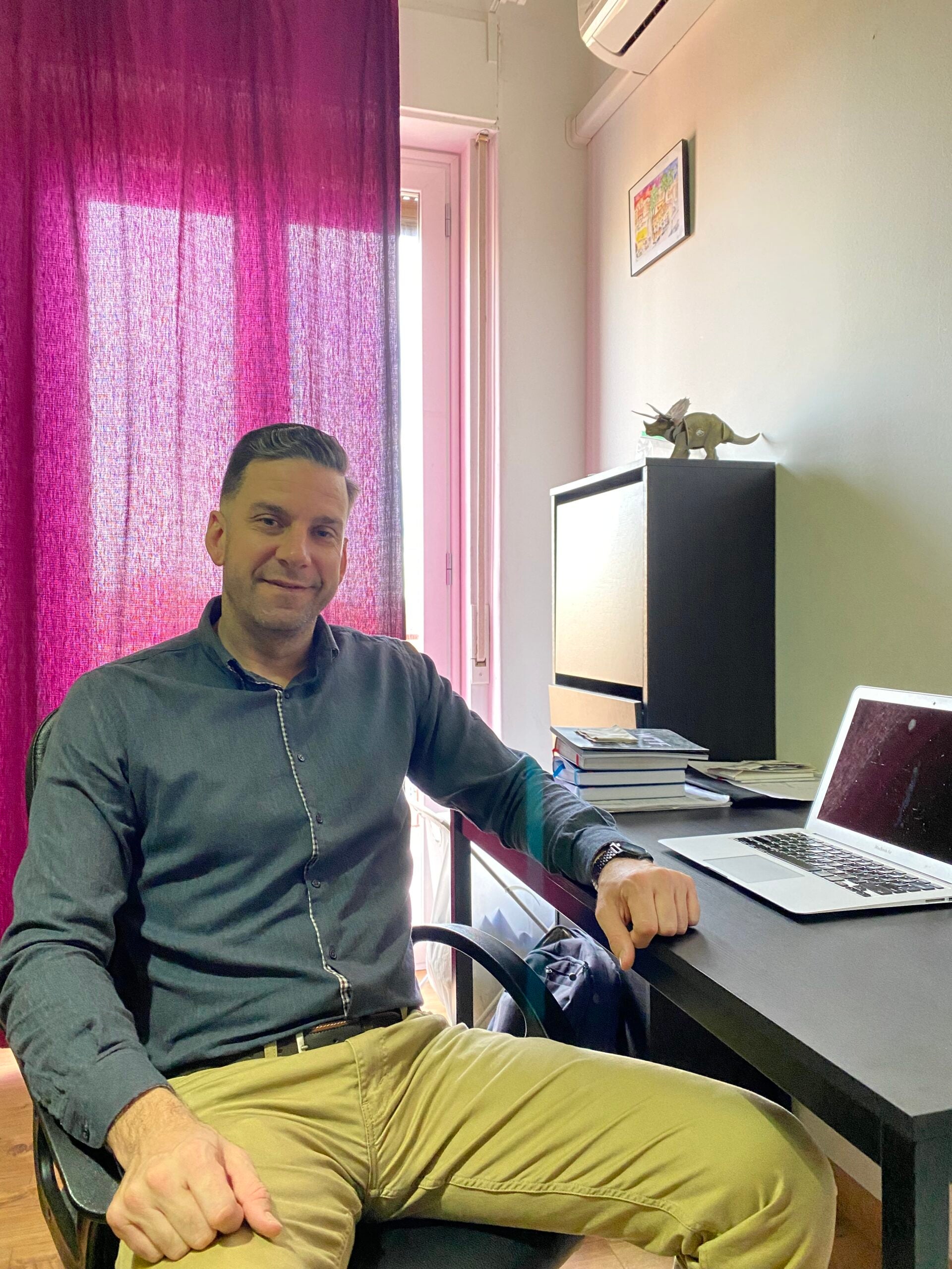 A Virtual Educator sitting at his desk with a laptop and facing the camera.